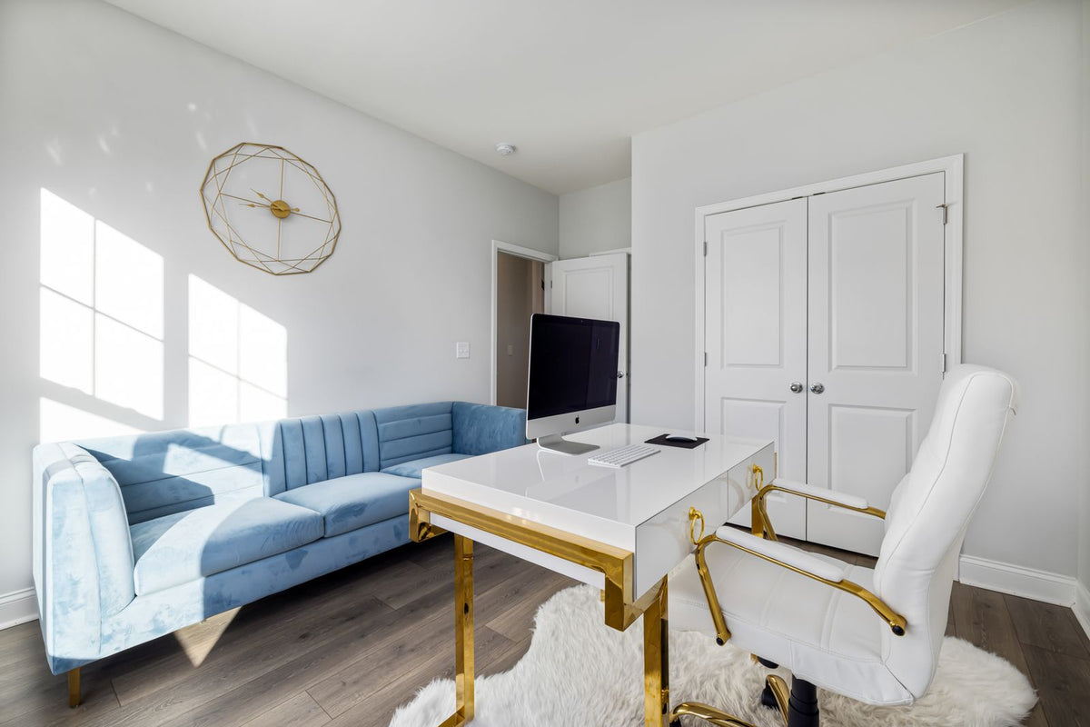 Light-blue sofa opposite a white desk and office chair in a bright home office.