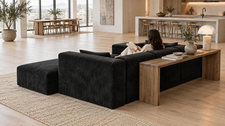 Black MONVANE L-Shaped Modular Couch floated in the middle of an open-plan room with a narrow console table behind it (AI-generated illustration, not a customer photo)