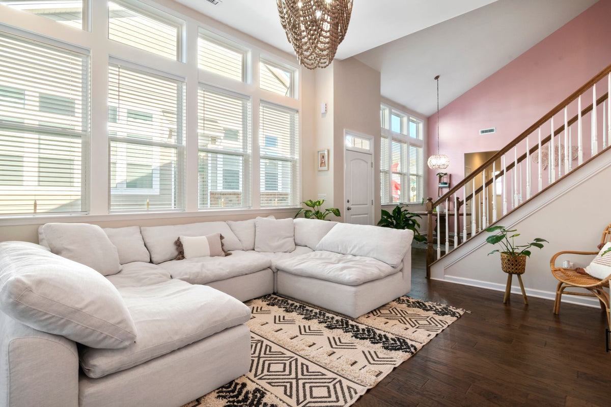 White corner sectional beside tall windows and a staircase.