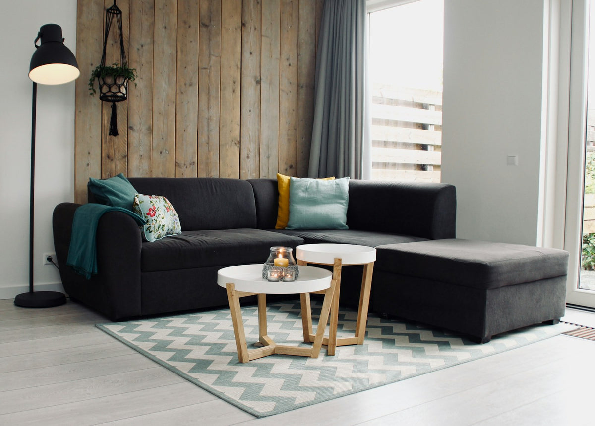 Black floor lamp beside the back corner of a charcoal sectional.