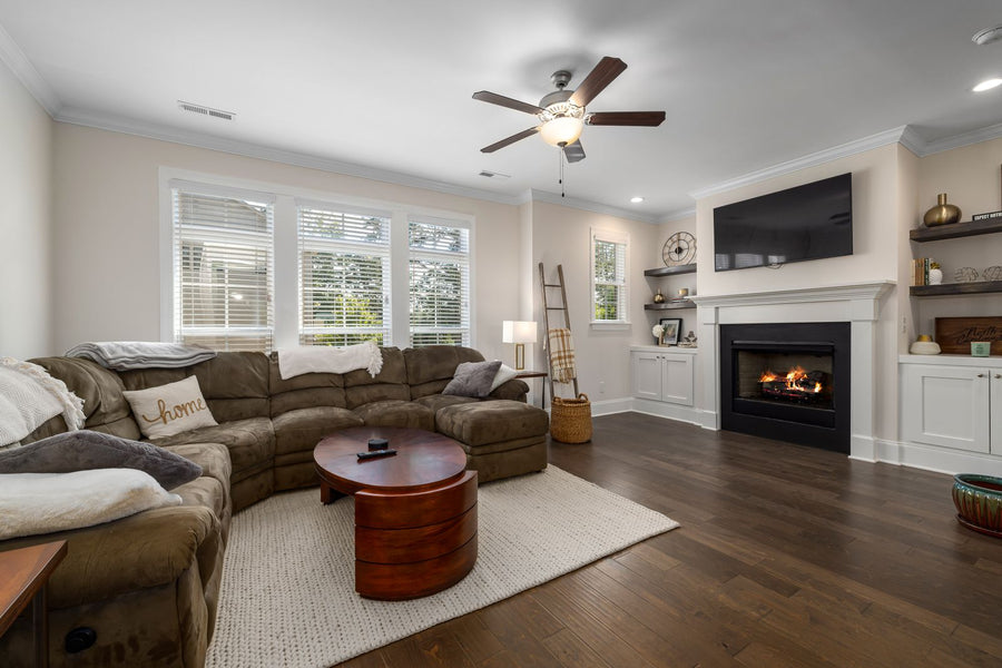 Brown corner sectional and round coffee table with open floor toward the fireplace.