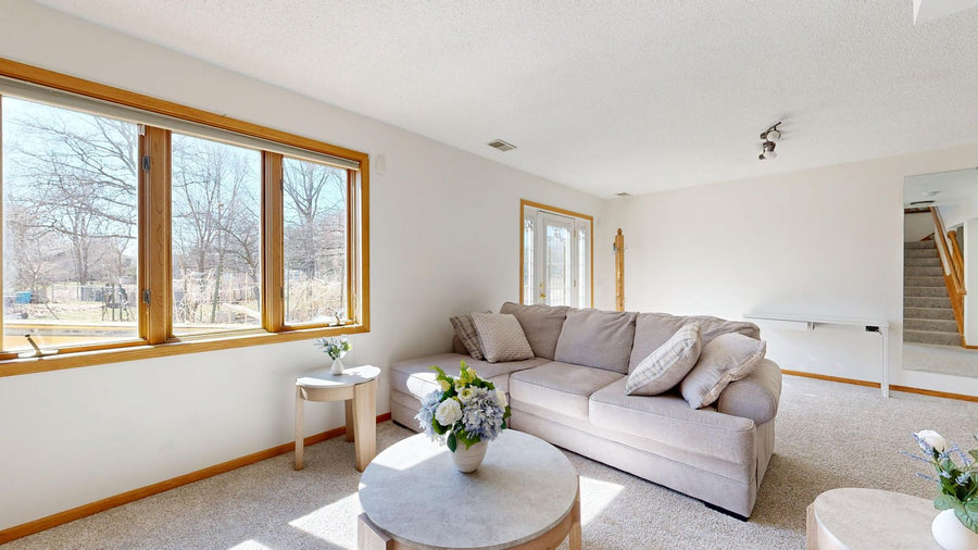 Beige sofa beside a small side table in a bright room with wooden window frames