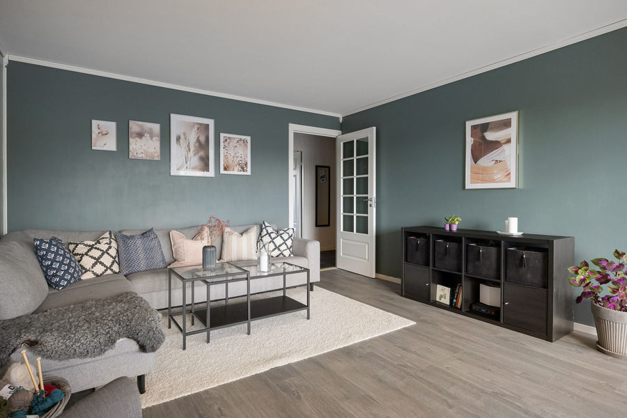 A gray chaise sofa beside a glass coffee table and an open doorway.