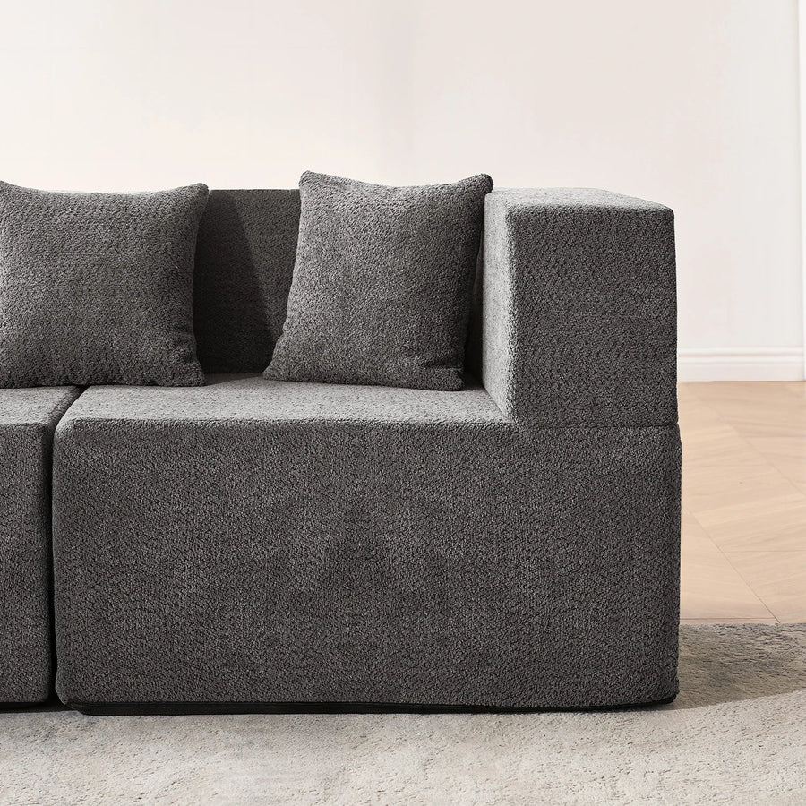 Close-up of dark gray sofa upholstery across arm, base and seat edge