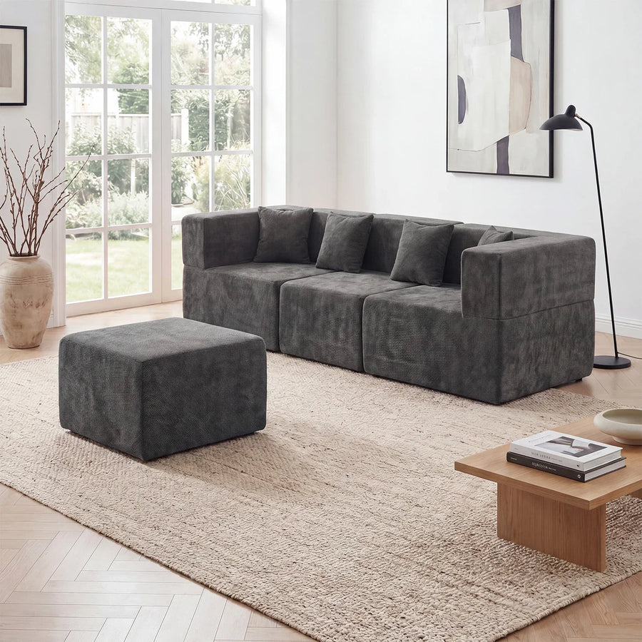 Dark-gray Monvane modular sofa in a straight run with a detached ottoman and open floor around it.