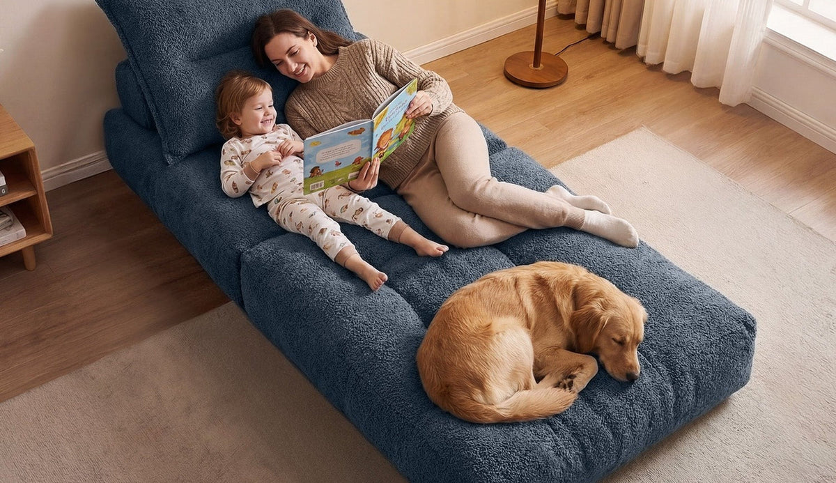 A woman and child reading on an open blue Monvane Oversized Sofa Bed while a dog rests near the foot.