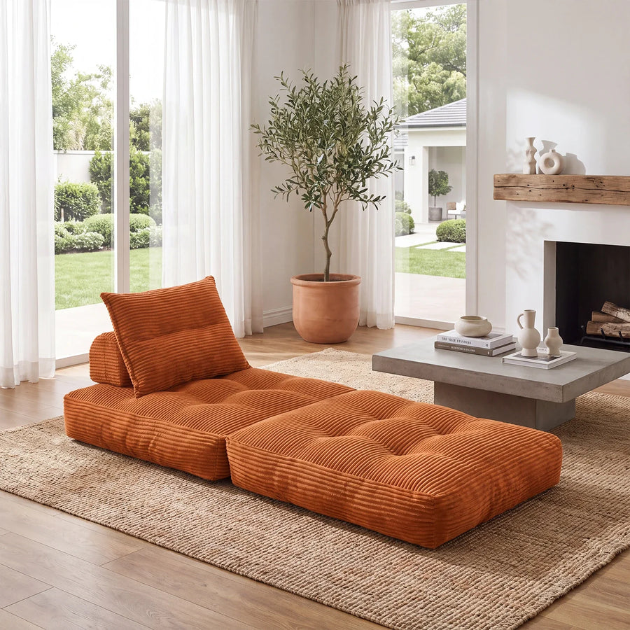 Orange single-unit sofa bed shown fully open on a rug in a bright room.