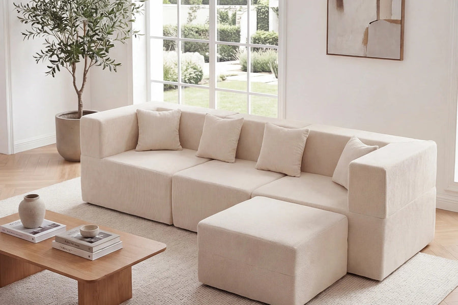 Light upholstered Monvane sectional arrangement with tonal pillows, separate module, rug and low wood table in a neutral room.