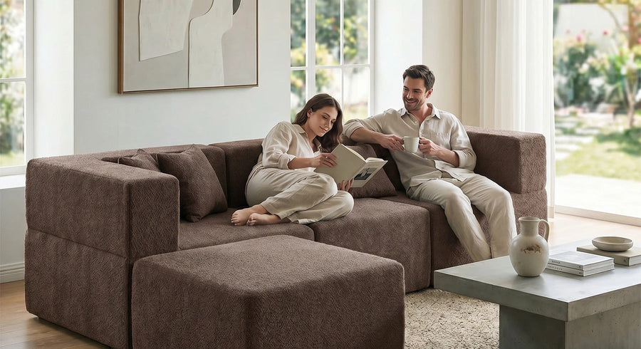 A couple seated on a brown Monvane modular sectional with visible seat modules and a separate ottoman.