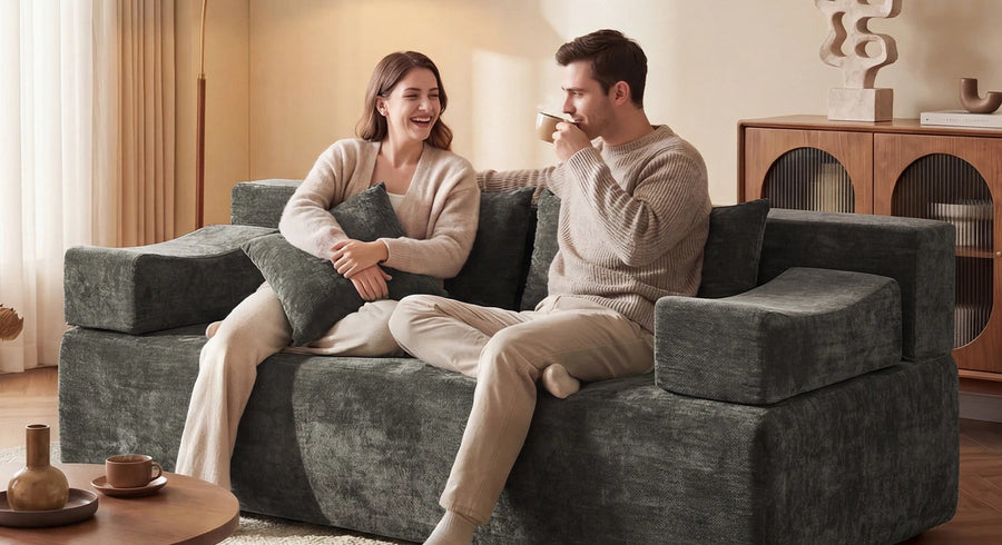 A couple sitting on a gray Monvane loveseat in a warm, bright living room.