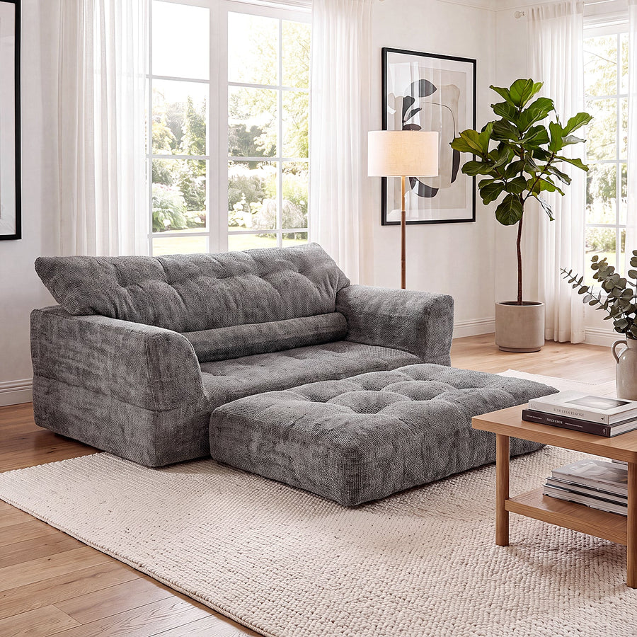 Dark-gray Monvane Convertible Loveseat with a separate upholstered footrest in a bright room.